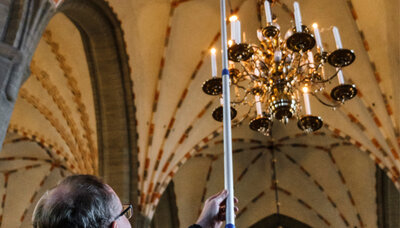 En man släcker en ljuskrona i en kyrka.