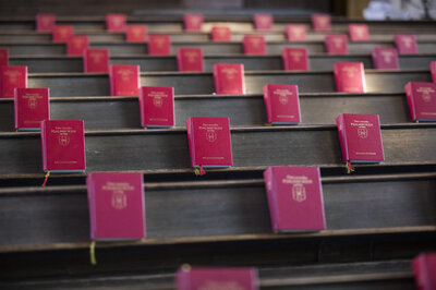 Psalmböcker prydligt uppställda med jämna mellanrum i kyrkbänkar.
