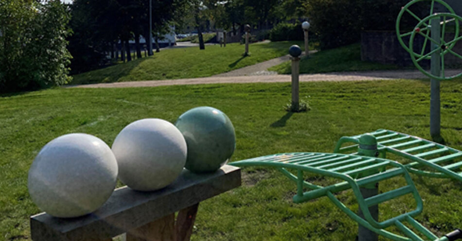 Stora modeller i keramik av Hemlighetspärlorna står uppradade på en piedestal i en park.