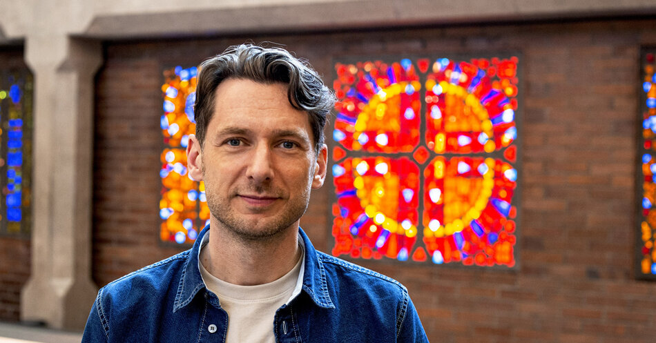 En glad man i  blå skorta i en kyrka med glasfönster | © Foto: Torleif Evermyr
