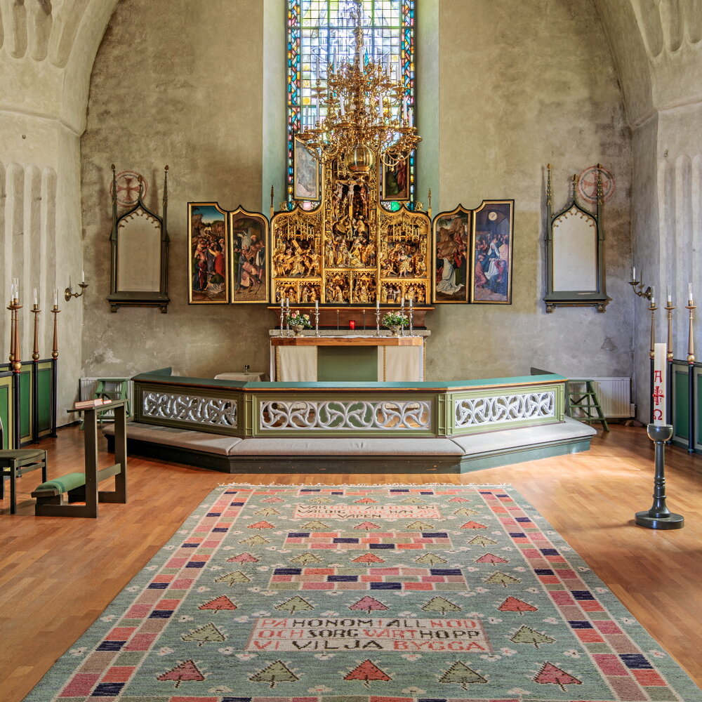 Altare med utvecklat förgyllt altarskåp i stenkyrka med trägolv.