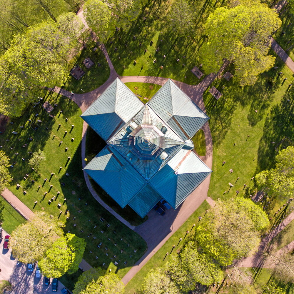 Drönar bild tagen rakt ovanför kyrka visar blå/grönt koppartak samt grön omgivning.