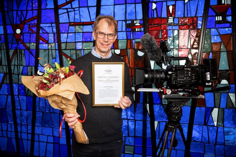 En man med blommor och ett diplom i ett kyrkorum | © Foto: Mikael M Johansson