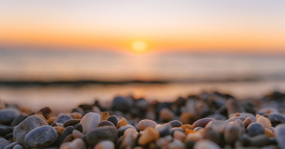 Stenar på en strand i solnedgång