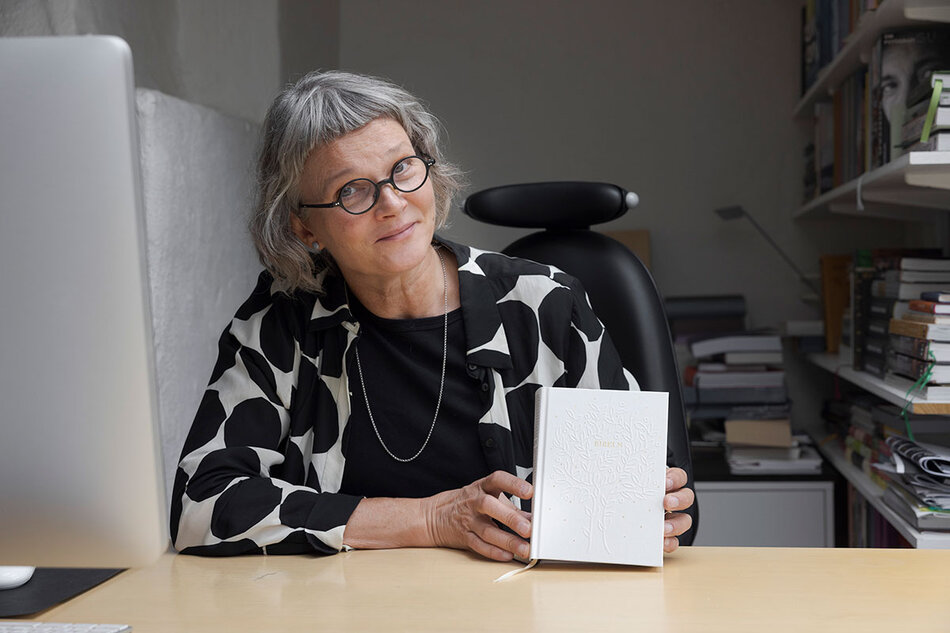 En kvinna med grått hår i en studio som visar upp en vit Bibel | © Foto: Mikael M Johansson