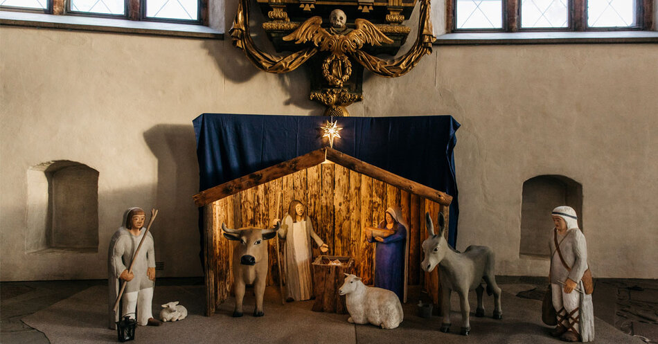 Närbild krubba i trä på golvet i en kyrka.