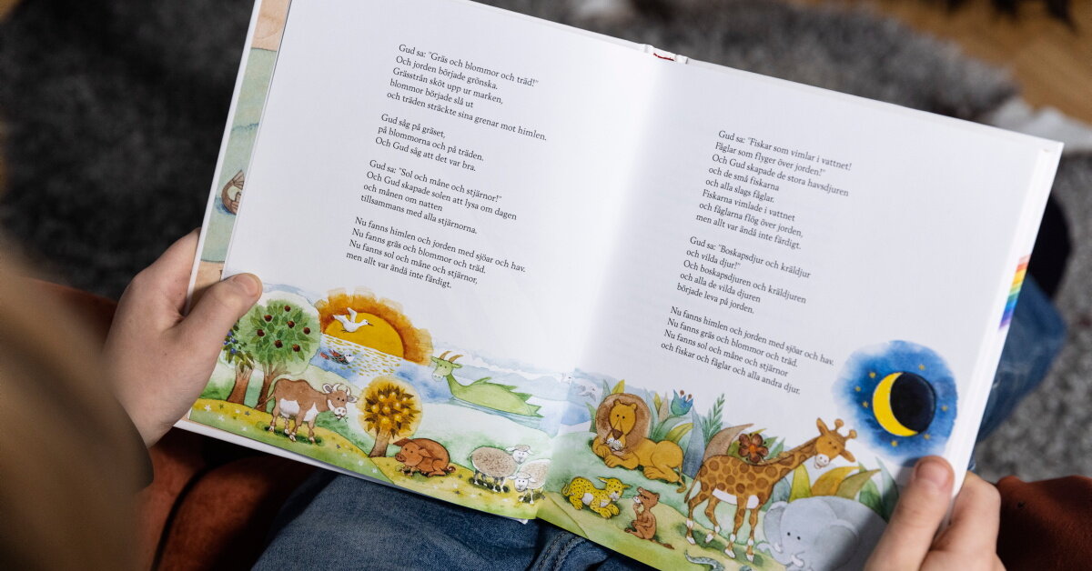Barn läser ur barnens bibel, på uppslaget visas berättelsen om hur Gud skapade världen.