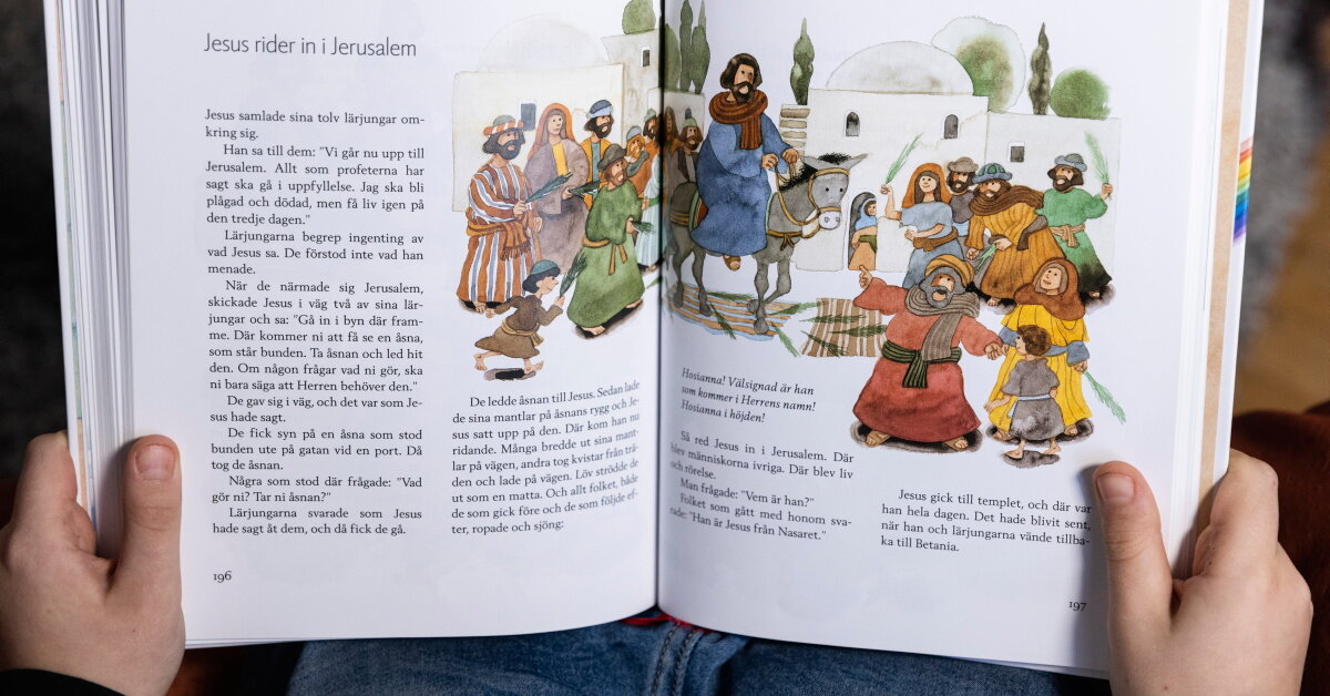 Barn läser ur barnens bibel, på uppslaget visas berättelsen om hur Jesus rider in i Jerusalem.