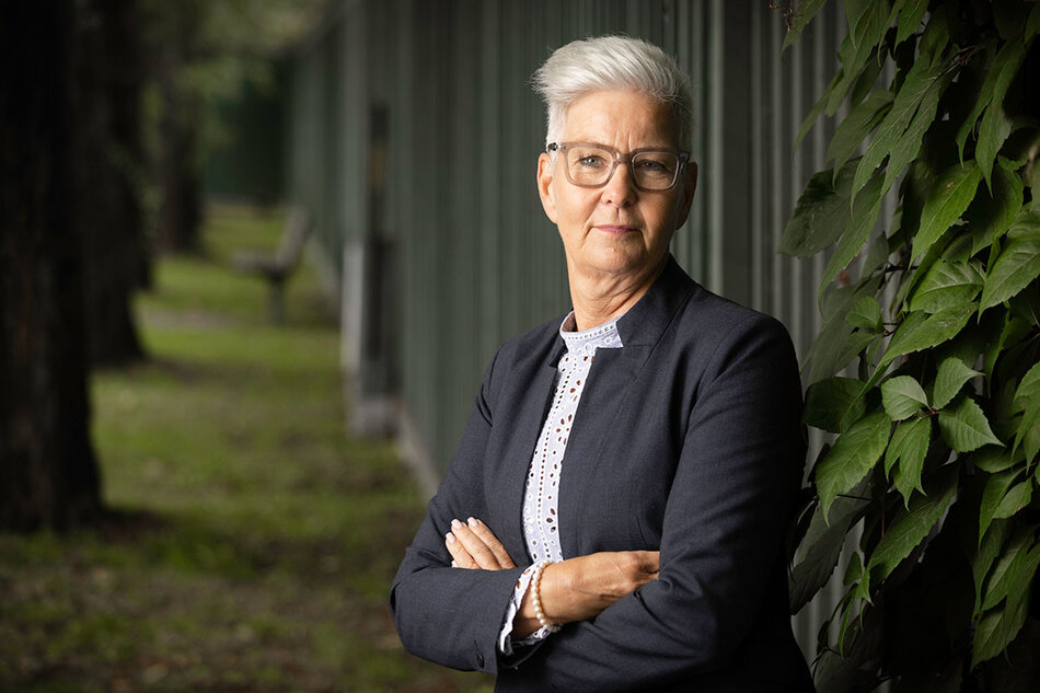 En medelålders kvinna står med armarna i kors framför ett plank. | © Foto: Mikael M Johansson