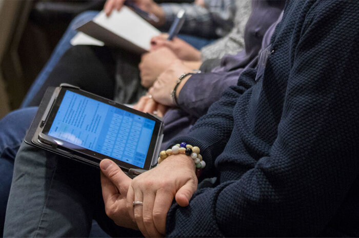 Konferensdeltagare med frälsarkrans på handleden och ipad i knät | © Mikael M Johansson