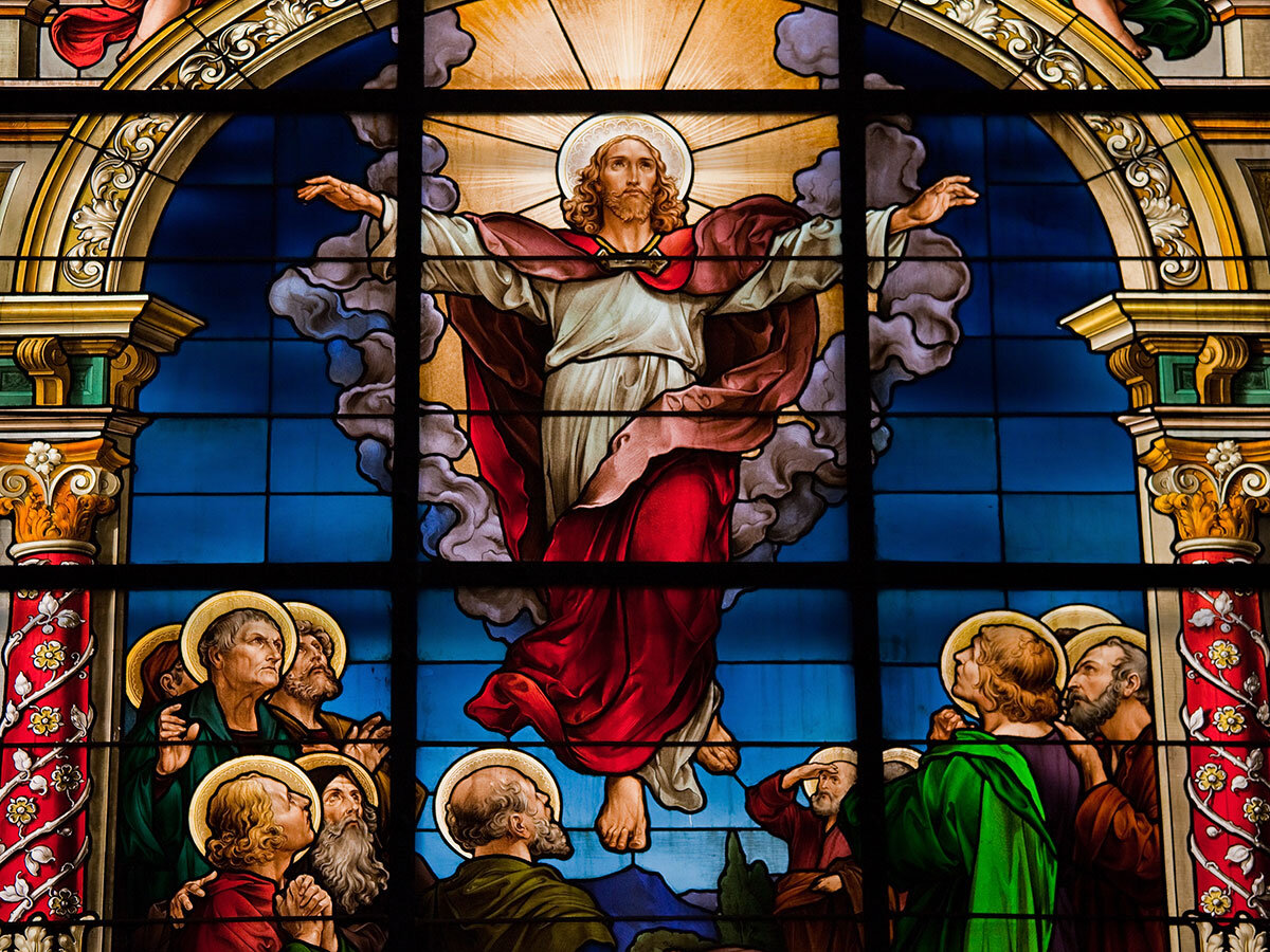 Färgat glasfönster som avbildar Jesus med en lysande gloria som svävar över lärjungarna.