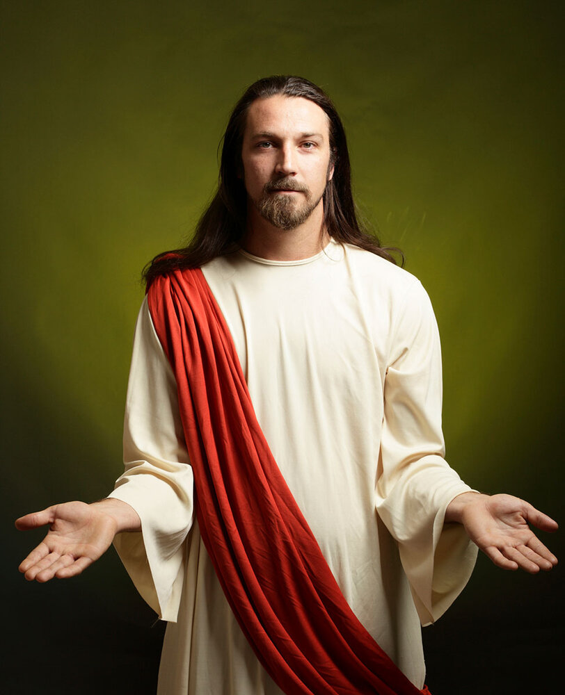 Porträtt av man som liknar Jesus står med utsträckta händer.
