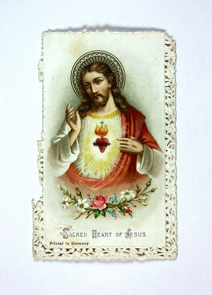 Jesus avbildad med ett lysande flammande hjärta vid bröstet med texten Sacred heart of jesus under.