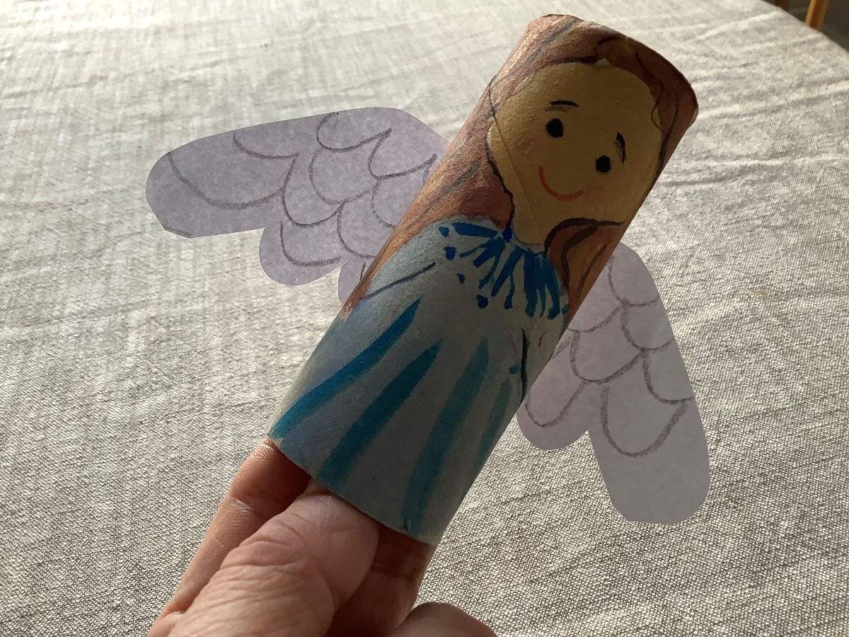 En ängel målad på en toa-pappersrulle i kartong med vita vingar.