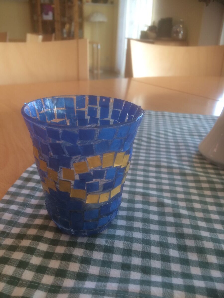 En glaslykta dekorerad med blåa rutor och ett guldigt mönster.
