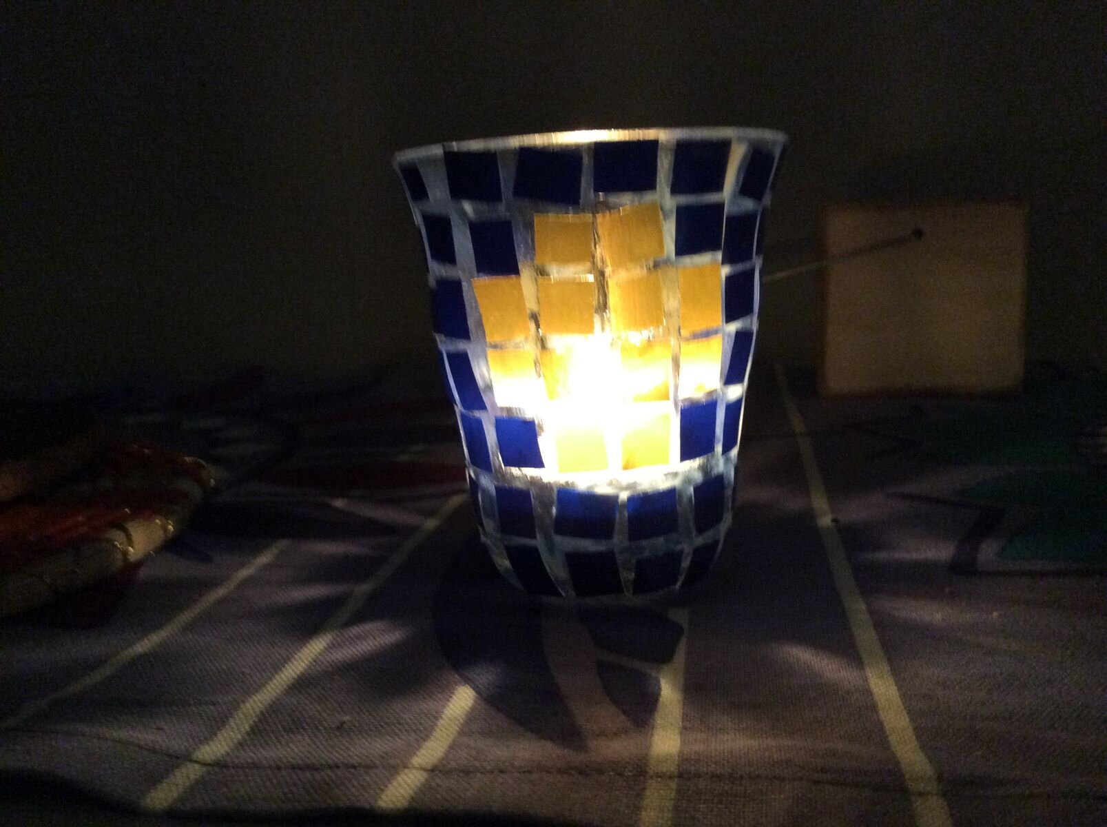 En glaslykta med ett tänt ljus i lyser upp ett mörkt rum.