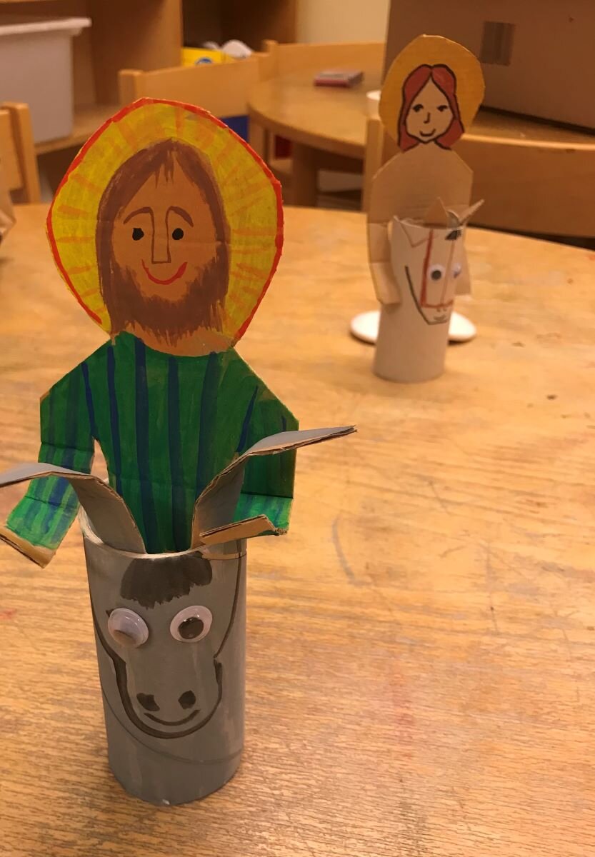 En Jesus figur av kartong ridandes på en kartong åsna.