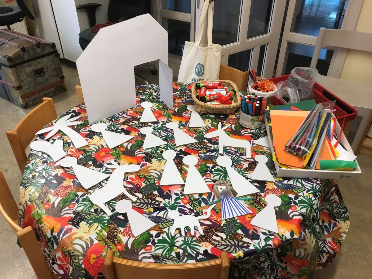 Ett runt bord täckt av urklippta figurer av kartong samt pyssel-material.